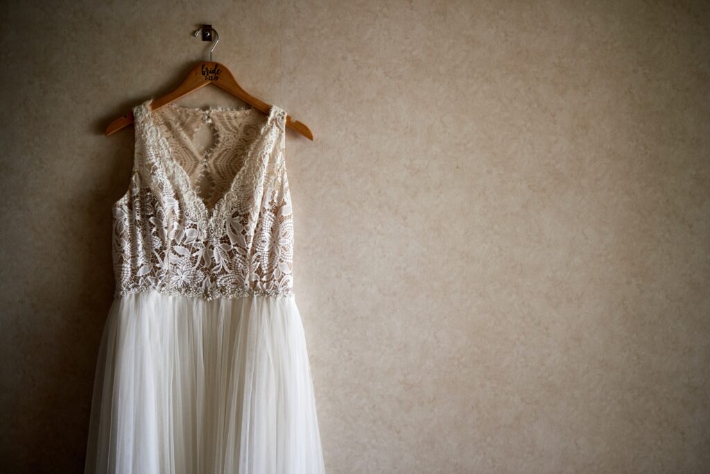White V-neck wedding dress hanging up on wedding morning