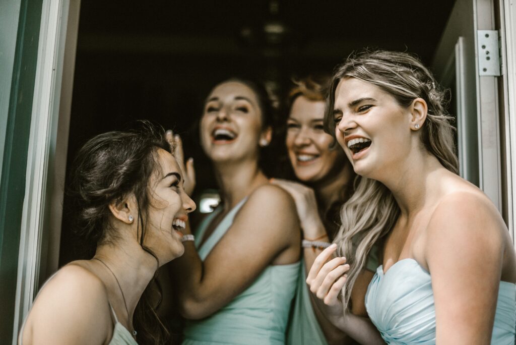 Bride with bridesmaids laughing and having fun while getting ready before wedding